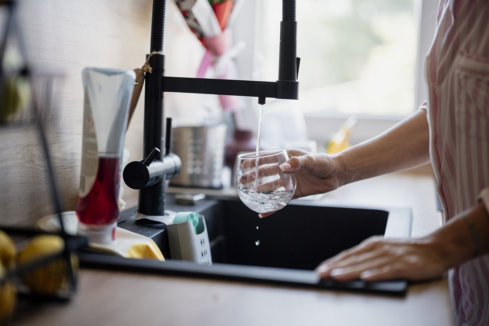 Glas wird am Wasserhahn gefüllt