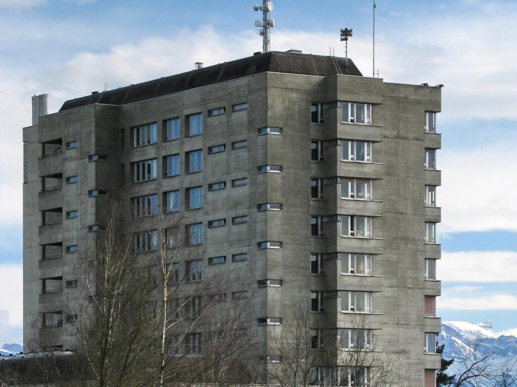 Das Hochhaus des GZO Spitals Wetzikon an der Spitalstrasse, davor Bäume, im Hintergrund die Alpen.